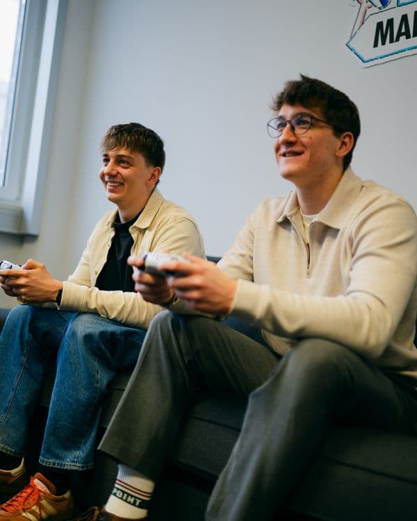 Zwei Crew-Mitglieder zocken gemeinsam auf der Couch im Ahoi Kapptn! Office